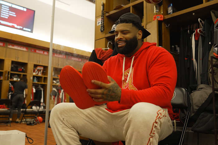 Trent Williams holds red sneakers in the San Francisco 49ers locker room.